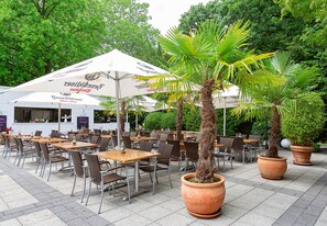 An outdoor cafe with tables and chairs, large umbrellas, and potted plants. - Dorint Kongresshotel Düsseldorf/Neuss (Neuss)