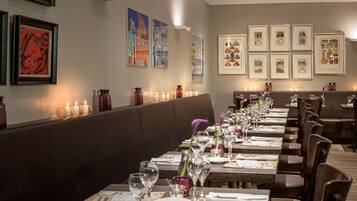 Un restaurante con una larga mesa de comedor dispuesta con velas, vasos y menús.