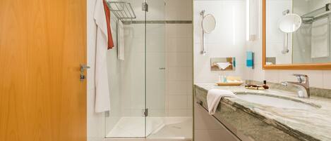 A modern bathroom with a glass shower enclosure, a marble countertop, and a large mirror.