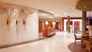 A hotel lobby with a reception desk, seating area, and decorative wall art. - Vienna House by Wyndham Baltic Stralsund (Stralsund)