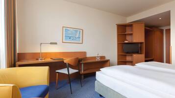 Une chambre d’hôtel avec un lit, un bureau, une chaise, une télévision et un tableau au mur.