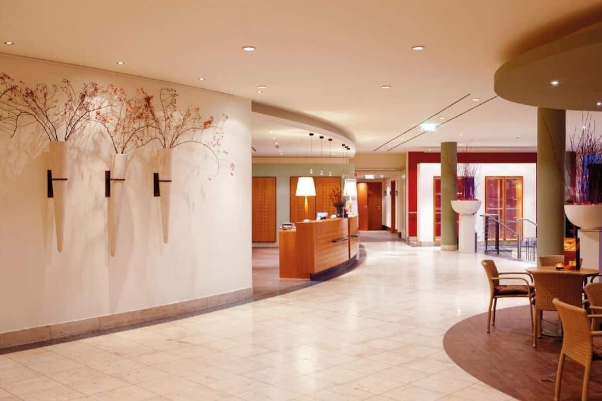 A hotel lobby with a reception desk, seating area, and decorative wall art.