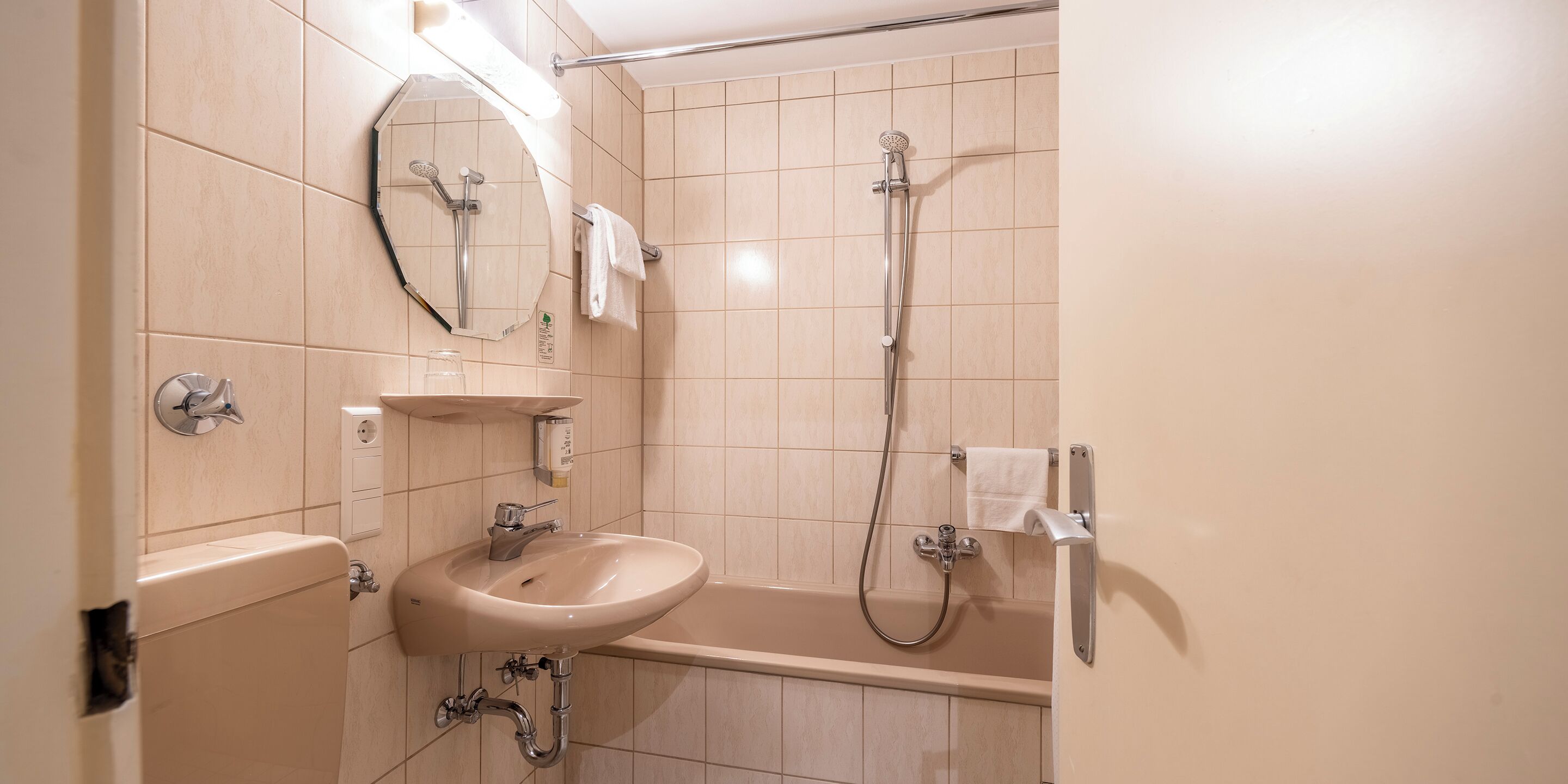A bathroom with a sink, mirror, and shower.