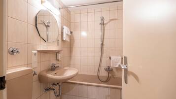 A bathroom with a sink, mirror, and shower.