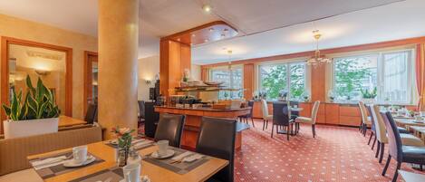 Un comedor de hotel con una barra central, varias mesas y sillas.
