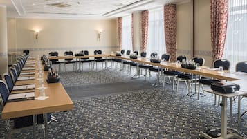 Un salón de conferencias con una mesa larga, sillas y piso alfombrado.