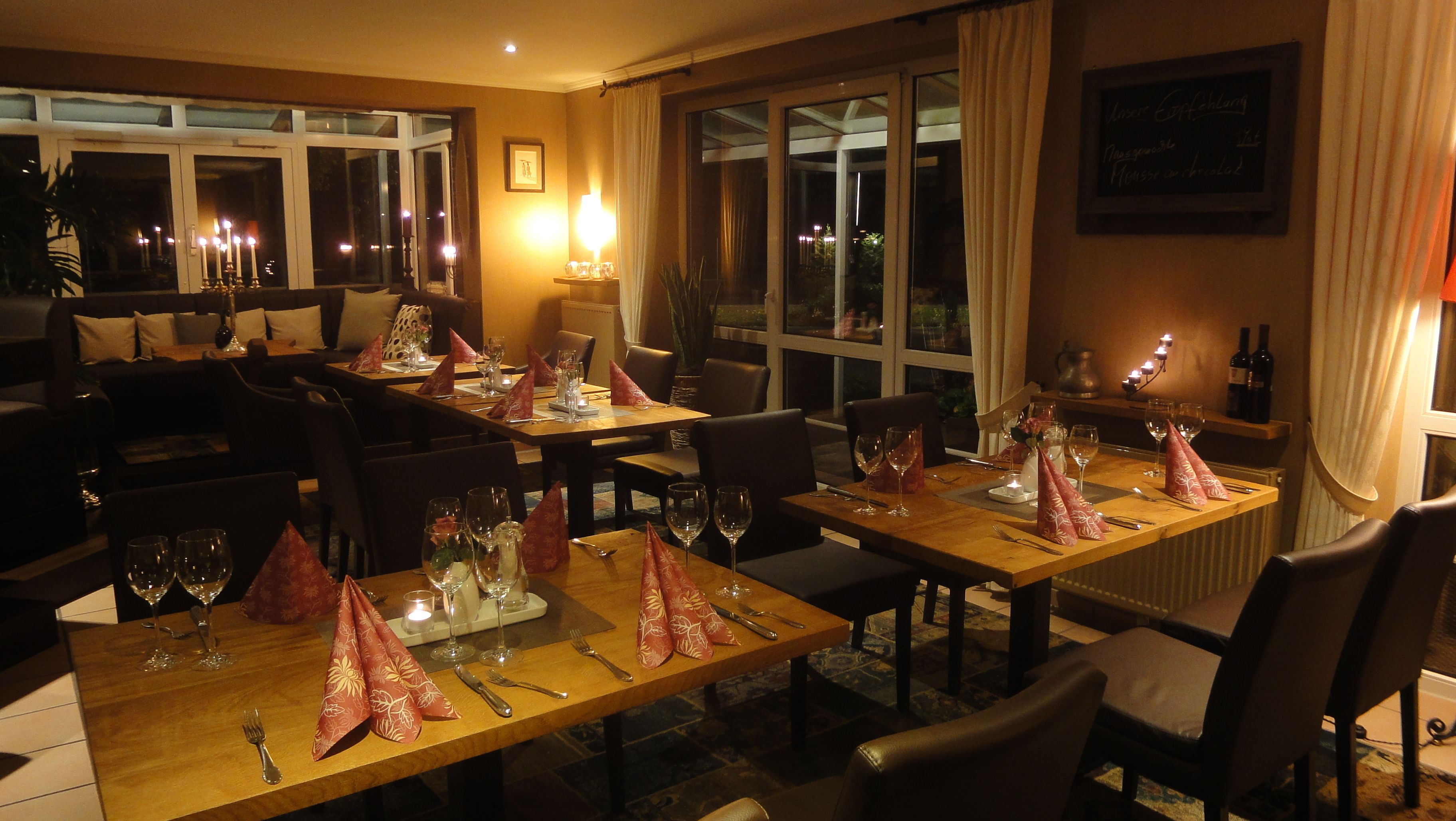 Ein Restaurant mit gedeckten Tischen, Kerzen und Servietten.