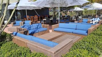 Outdoor seating with wicker furniture and blue cushions, surrounded by greenery.