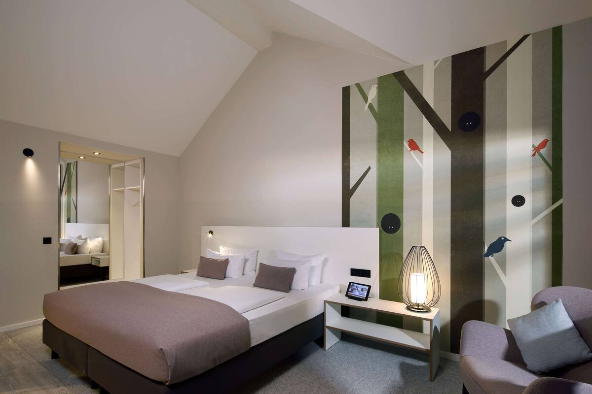 A modern bedroom with a large bed, bedside tables, a nightstand, and a chair.