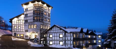 Un edificio tradicional europeo con una torre en esquina y numerosas ventanas, rodeado de nieve.