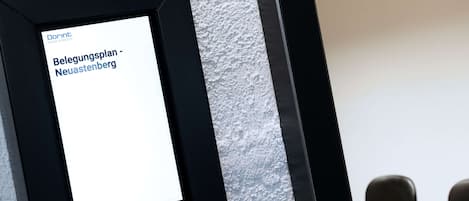 A framed sign with text in German, mounted on a textured wall.