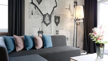 A modern living room with a grey sofa, multiple cushions, a floor lamp, and a vase with flowers.