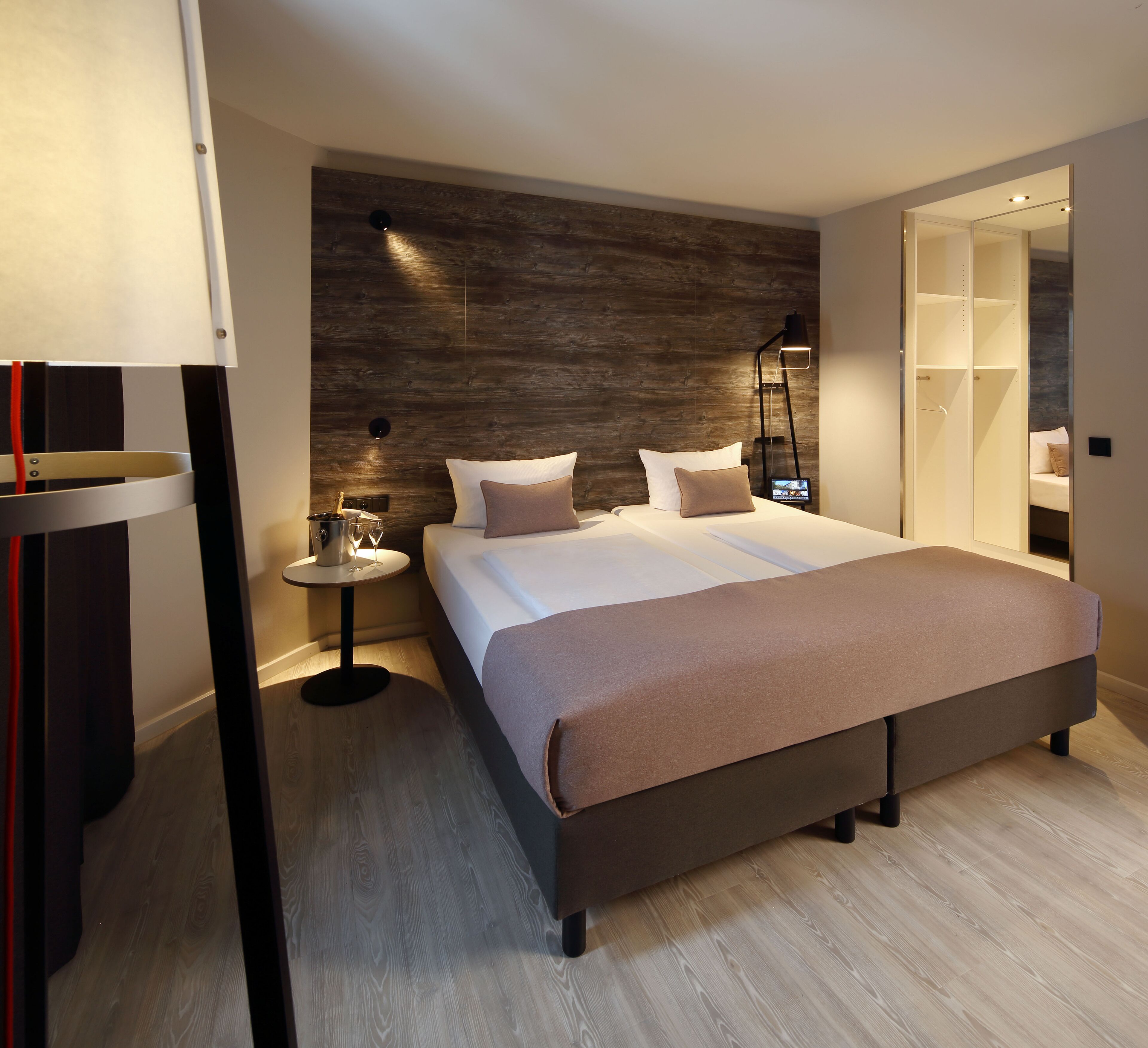 Ein modernes Schlafzimmer mit einem großen Bett, Nachttischen, einem Beistelltisch und einem Kleiderschrank.
