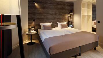 Ein modernes Schlafzimmer mit einem großen Bett, Nachttischen, einem Beistelltisch und einem Kleiderschrank.