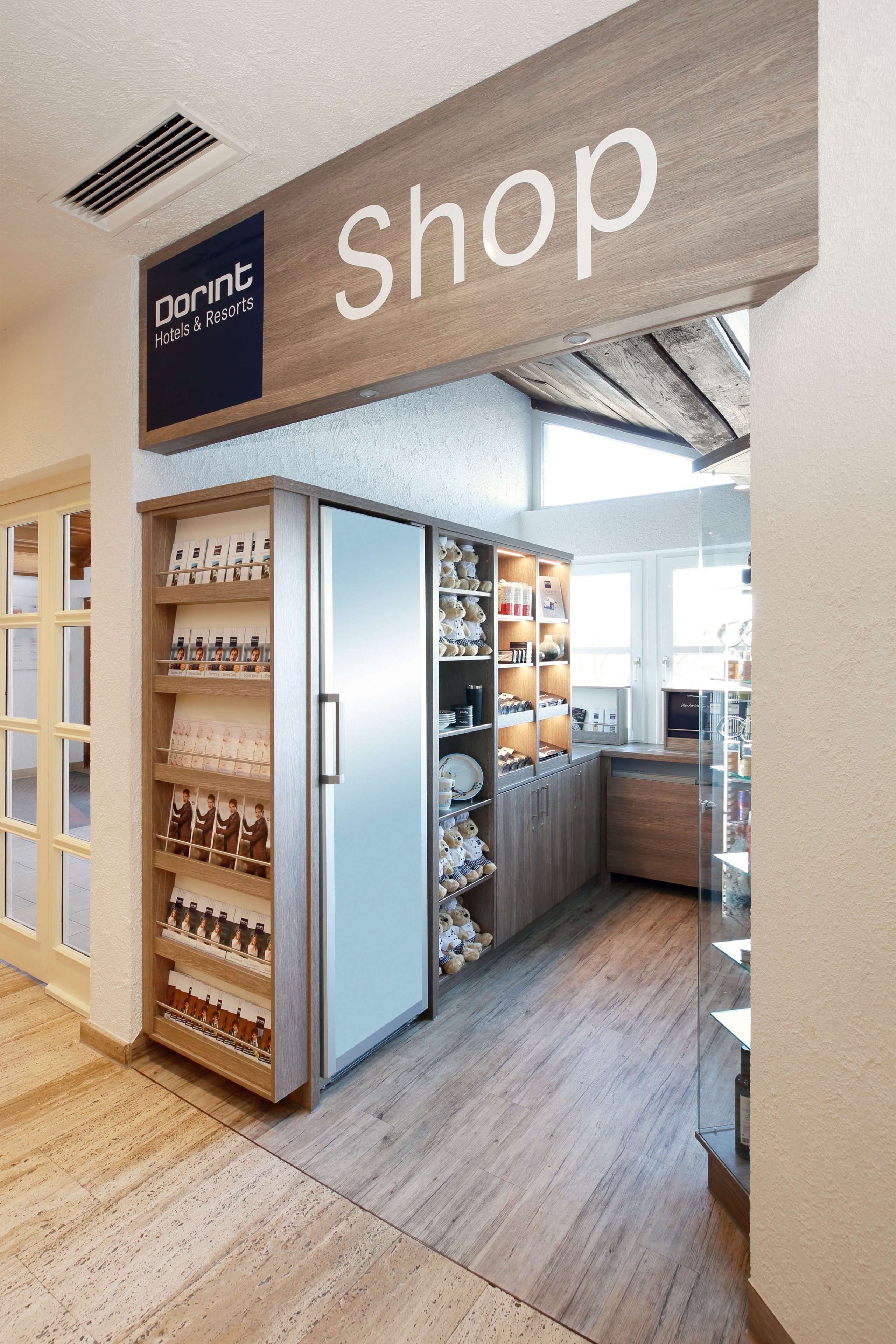 A Dorint Hotels & Resorts shop with a wooden sign, a refrigerated display case, and a variety of items on shelves.