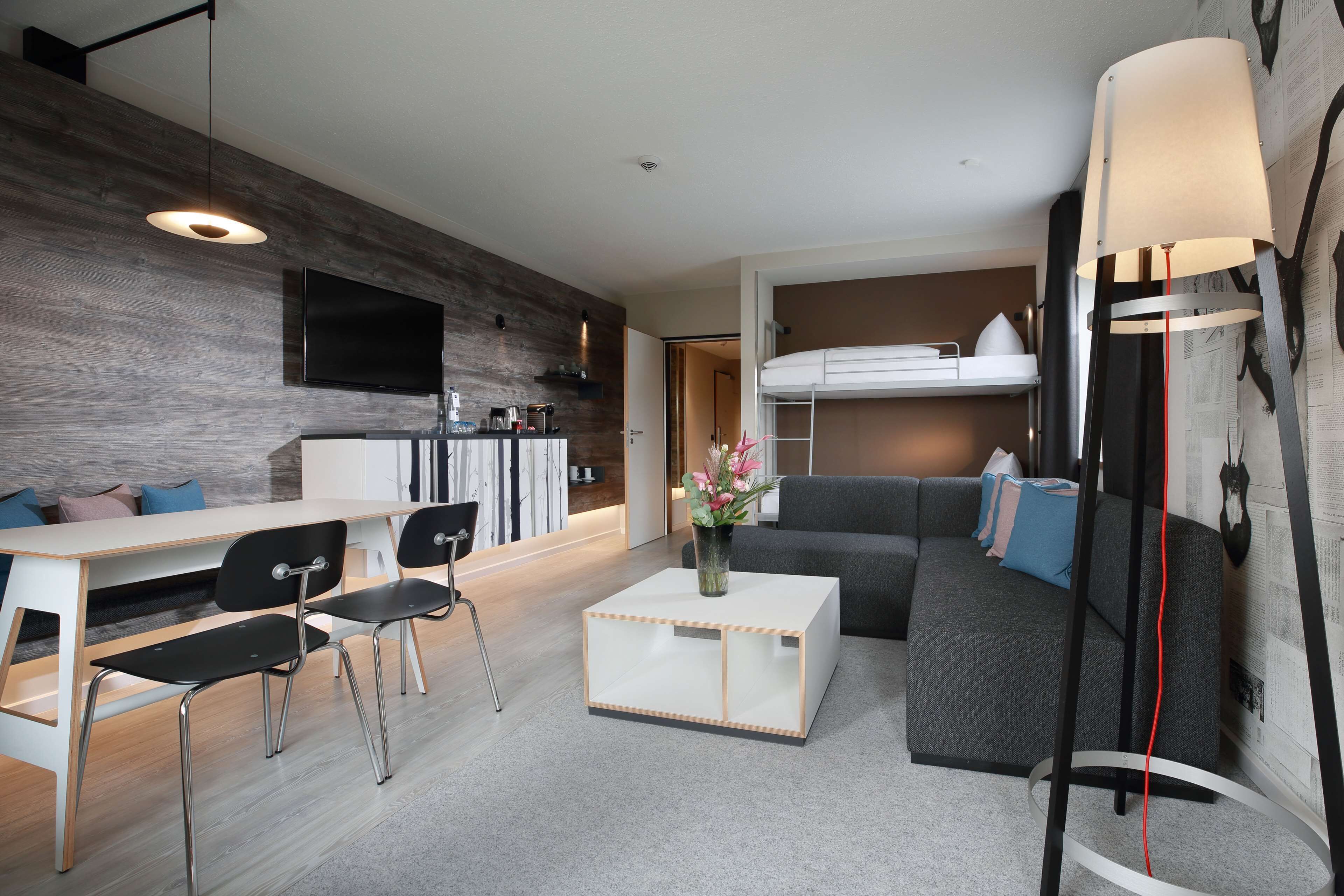 A modern living room with a sofa, a coffee table, a TV, and a bunk bed.