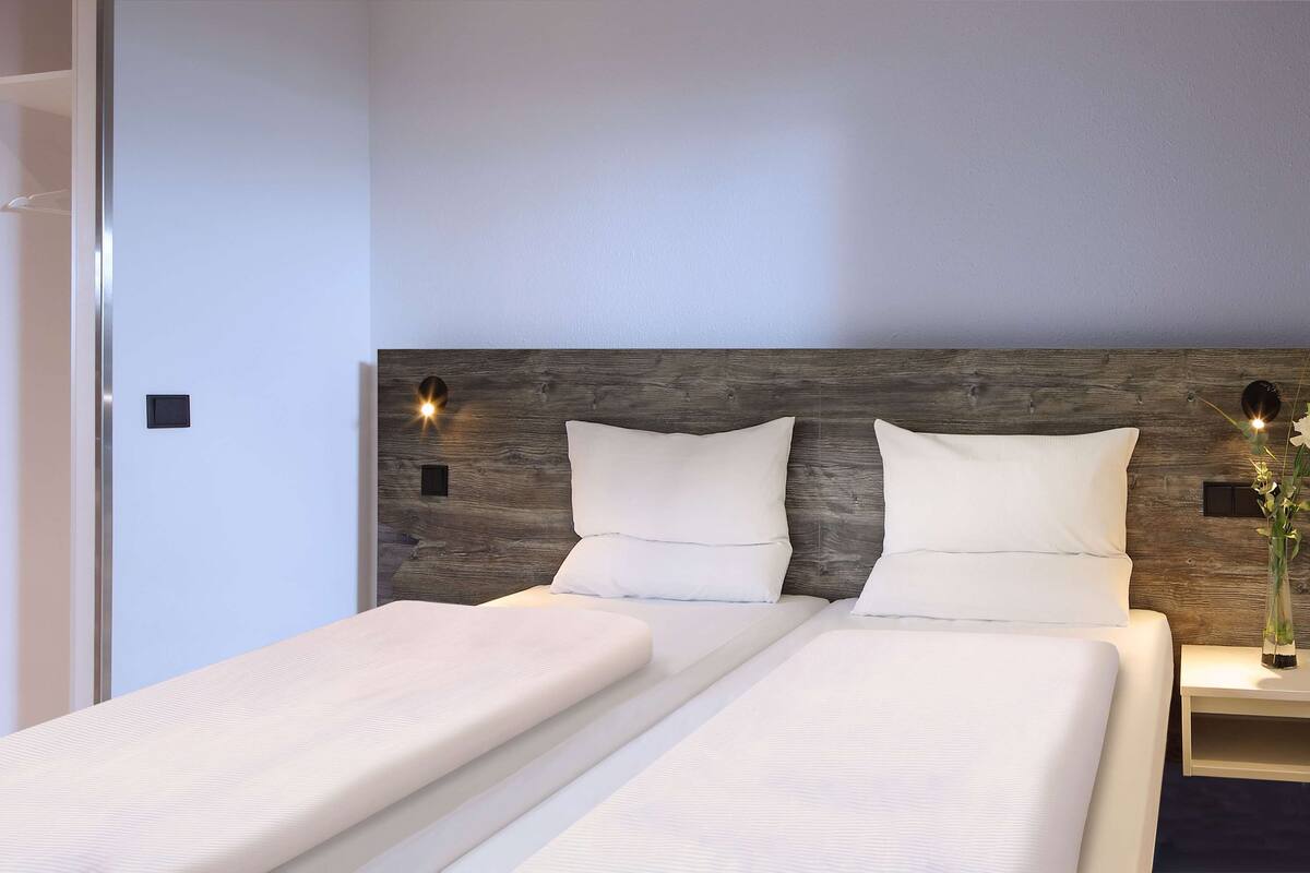 A double bed with a wooden headboard and two bedside tables, one with a vase.