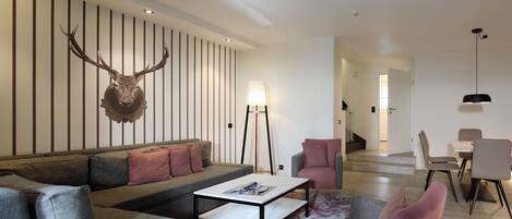 A modern living room with a sectional sofa, a coffee table, and a mounted deer head on the wall.