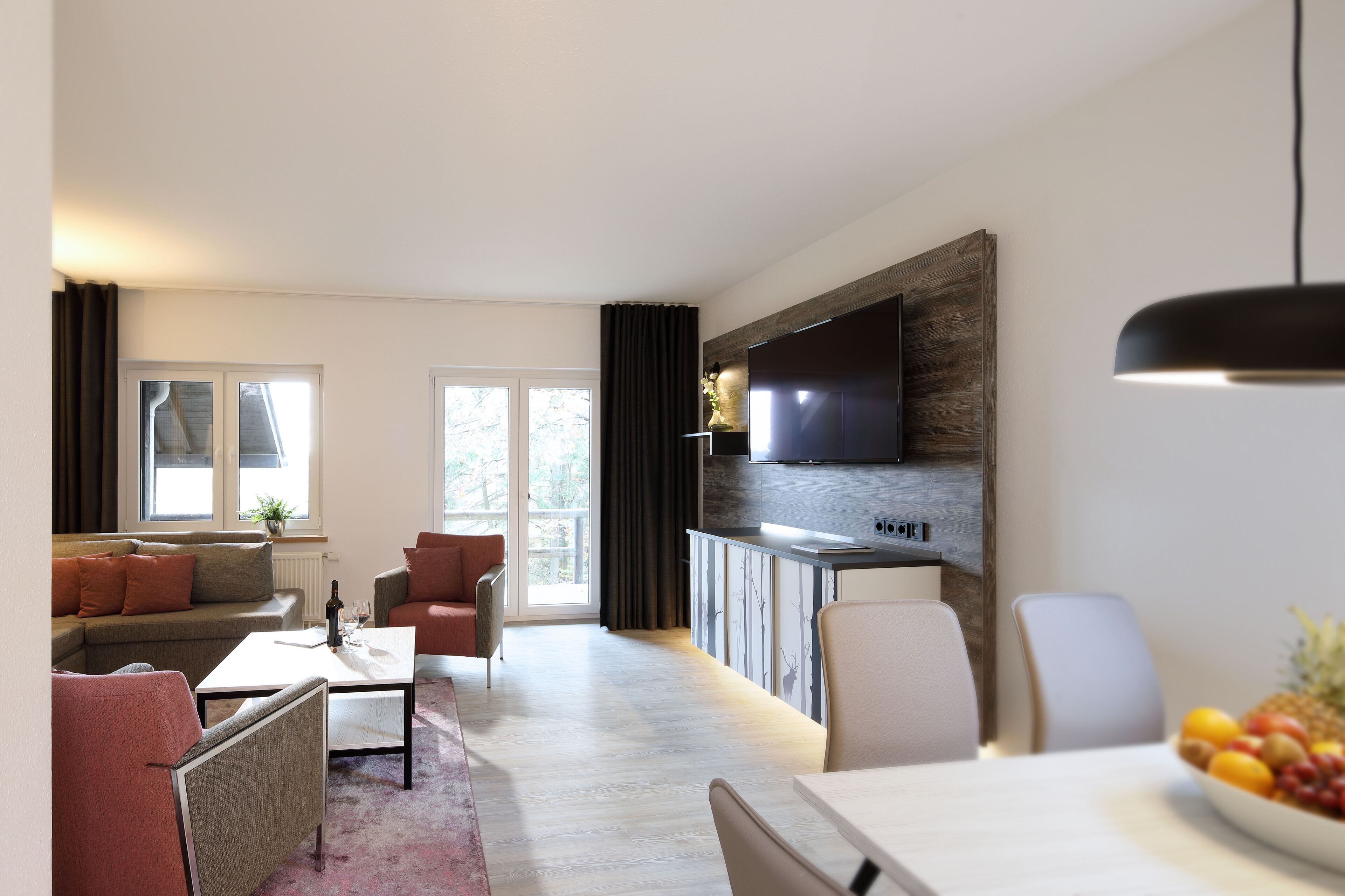 Un salon moderne comprenant un canapé, des fauteuils, une table basse et un coin repas avec une table et des chaises.