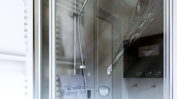 A modern bathroom with a glass shower enclosure, a towel rack, and a soap dispenser.