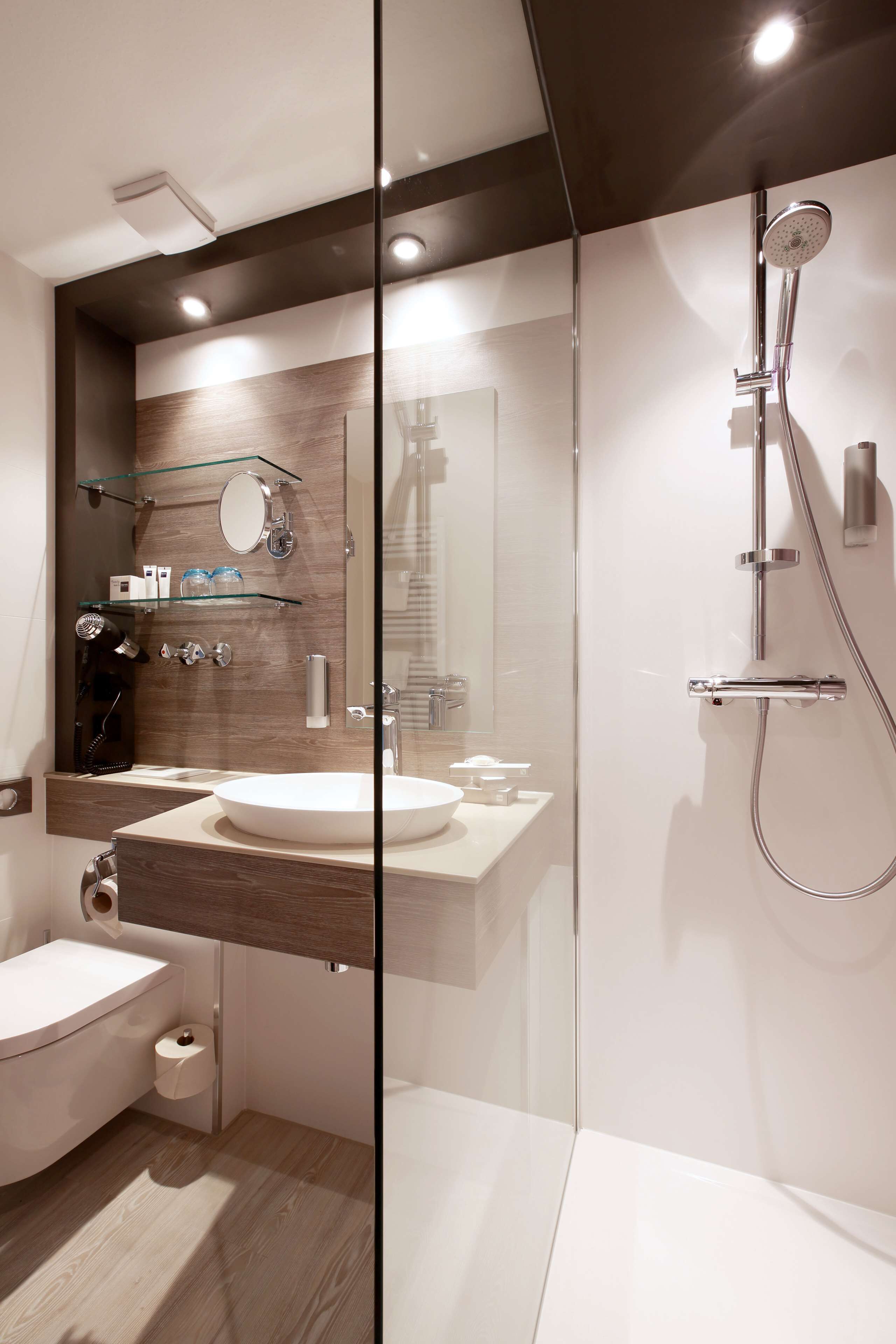 Une salle de bain moderne avec une douche à parois de verre, un lavabo blanc et un miroir au-dessus.