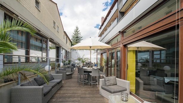 An outdoor patio area with wicker furniture, a table, and umbrellas.