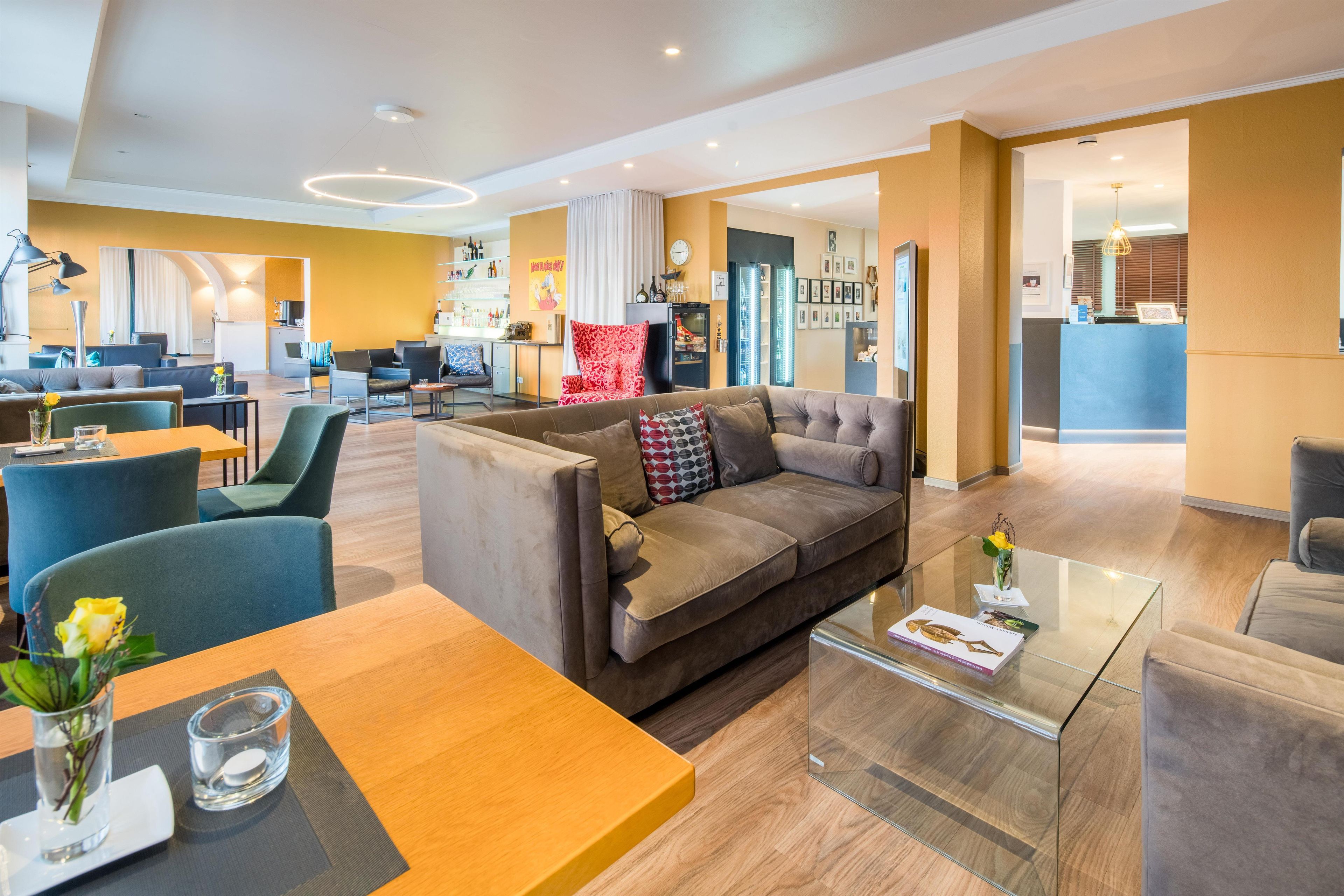 En modern hotellobby med en sittgrupp, en bar och en receptionsdisk.