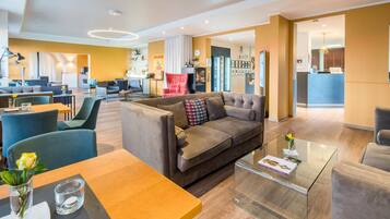 Eine moderne Hotelhalle mit Sitzgelegenheiten, einer Bar und einer Rezeption.