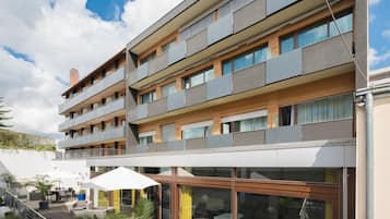 Ein mehrstöckiges Wohngebäude mit Balkonen, Sitzgelegenheiten im Freien und einem Glastürbereich.