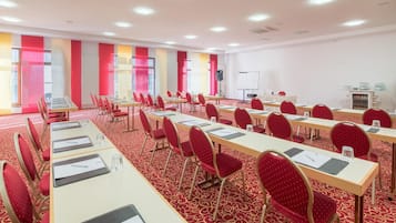 A conference room with rows of tables and chairs, a whiteboard, and a projector.