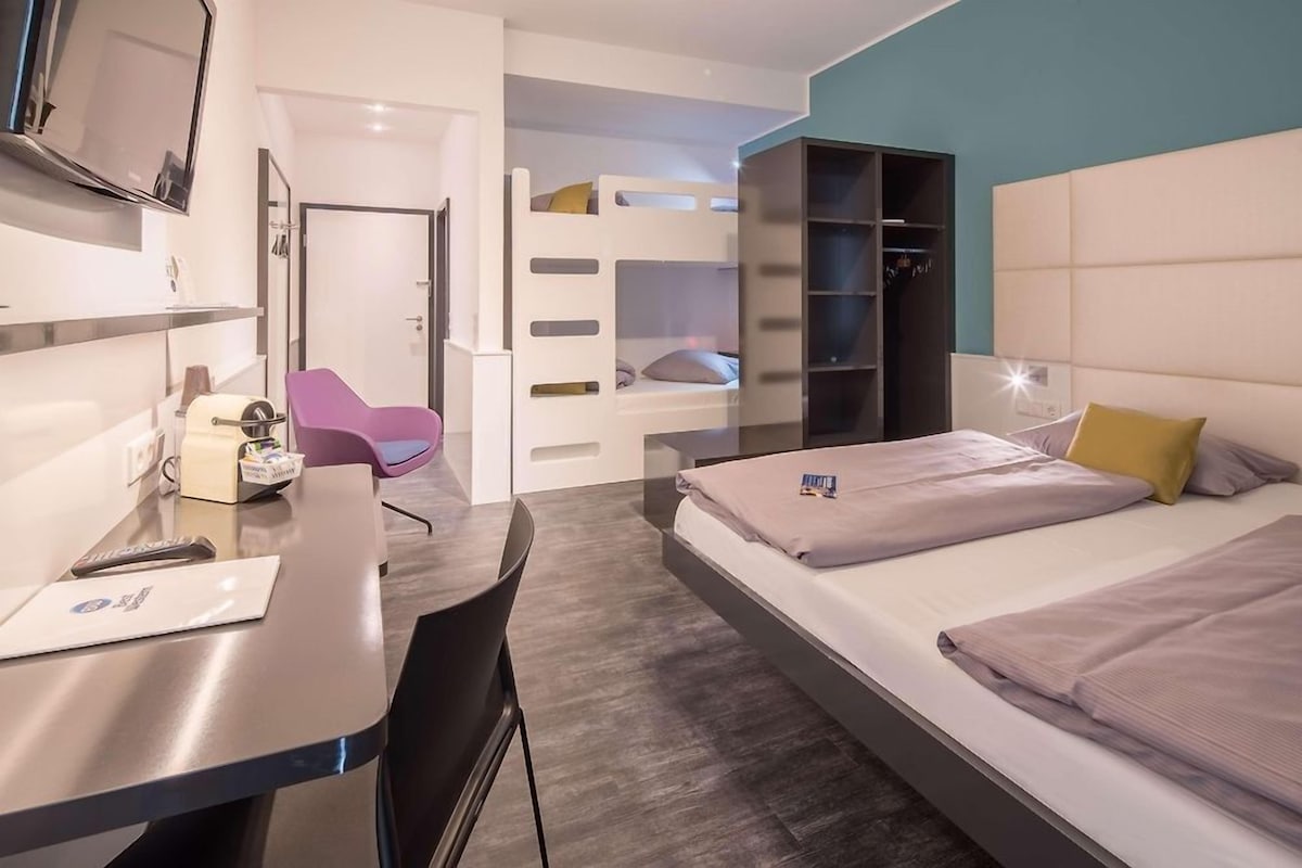Een moderne hotelkamer met een bed, een bureau met stoel, een televisie en een kledingkast.