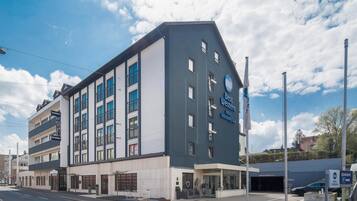 En modern hotellbyggnad med en tydlig skylt med texten ”Best Western”, flera balkonger och en parkeringsplats.