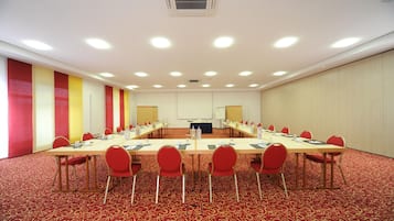 A conference room with a long table, red chairs, and a carpeted floor.