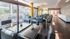 A modern hotel lobby with glass partitions, leather seating, and a reception desk.