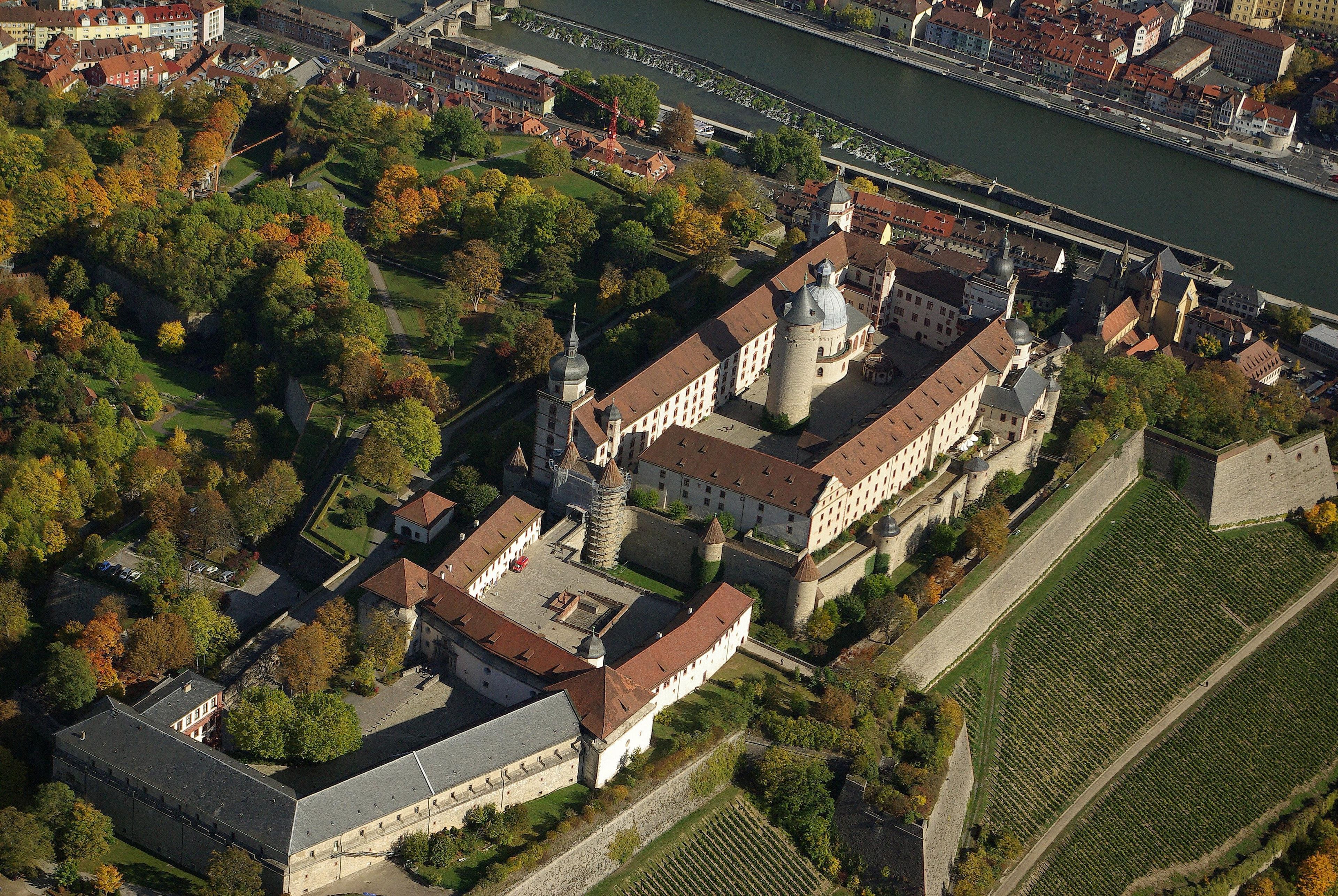 An aerial view of a historic building complex with a river in the background.