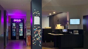 A hotel reception area with a reception desk, a self-check-in kiosk, and a neon sign in the background. - Best Western Hotel Wuerzburg Sued (Würzburg)