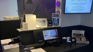 A reception desk with a computer, a self-check-in kiosk, and informational posters. - Best Western Hotel Wuerzburg Sued (Würzburg)
