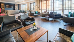 A spacious living area with leather sofas, a wooden coffee table, and large windows providing natural light.