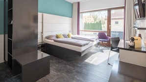 A modern hotel room with a bed, a desk, a chair, and a TV.