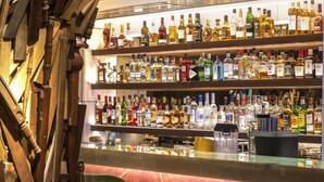 A bar area with wooden decor and multiple shelves of liquor bottles. - New Hotel (Athens)