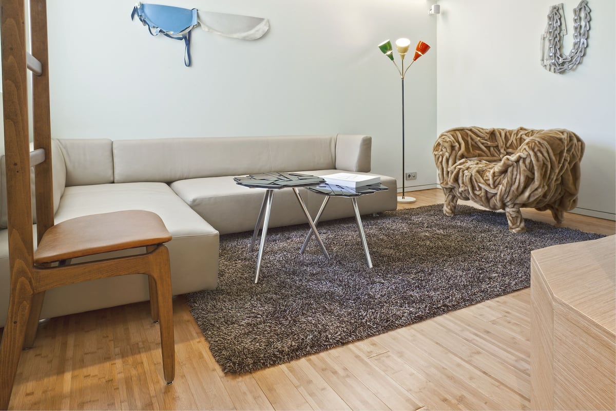 Una sala moderna con un sofá modular, una mesita de madera, una lámpara de pie y una alfombra con forma de cerebro.
