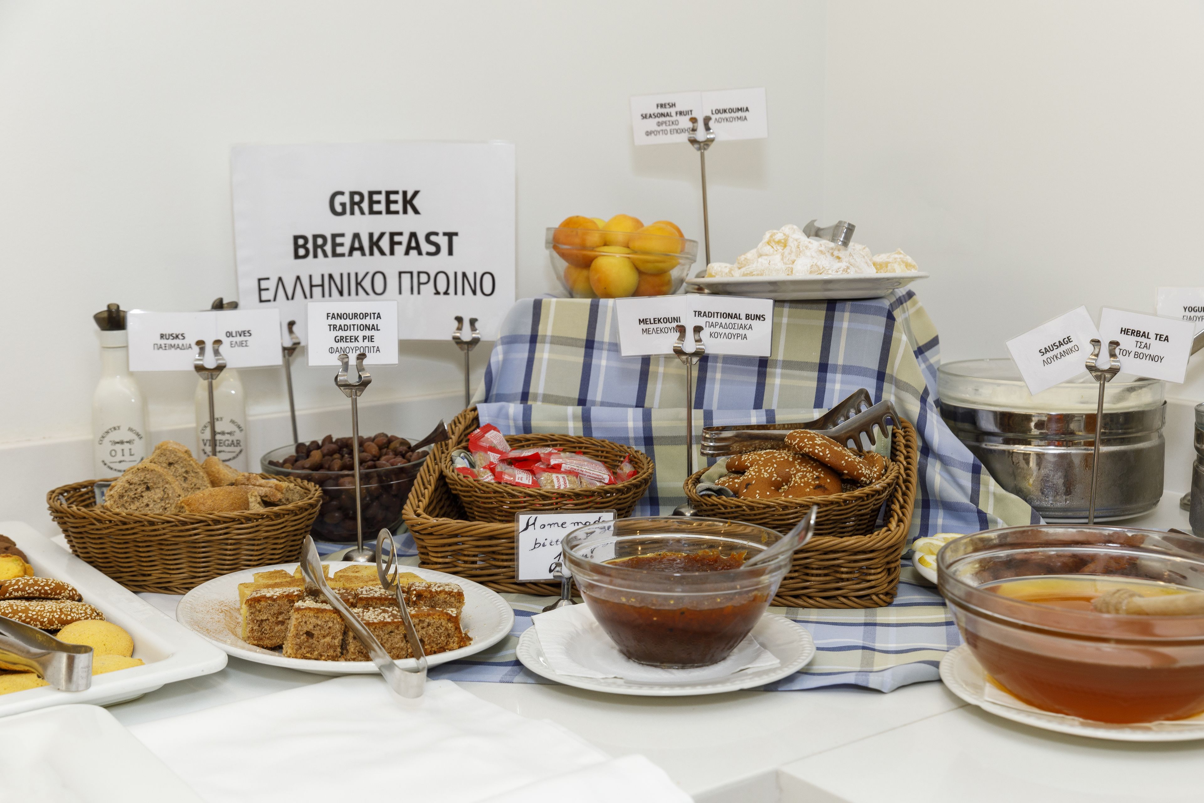 Un bufé de desayuno con diversos platos griegos, incluyendo aceitunas, pan y miel.