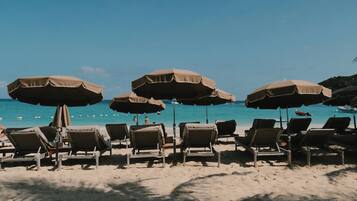 A beach with sun loungers and umbrellas.
