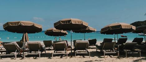 Una playa con tumbonas y sombrillas.
