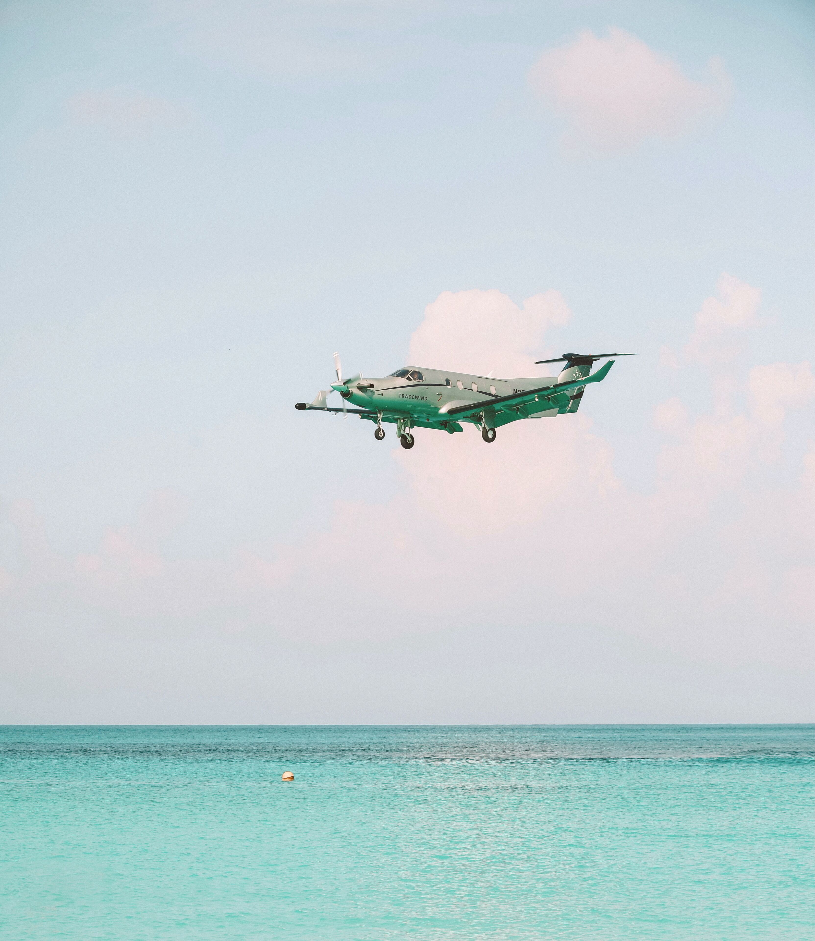 A small aircraft flying over a calm sea.