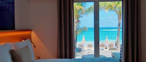 A hotel room with a bed, curtains, and a view of the beach.