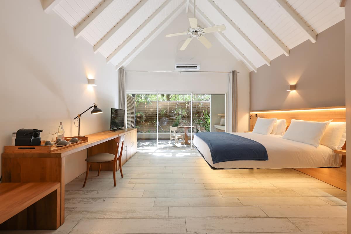 A bedroom with a bed, desk, chair, and a ceiling fan.