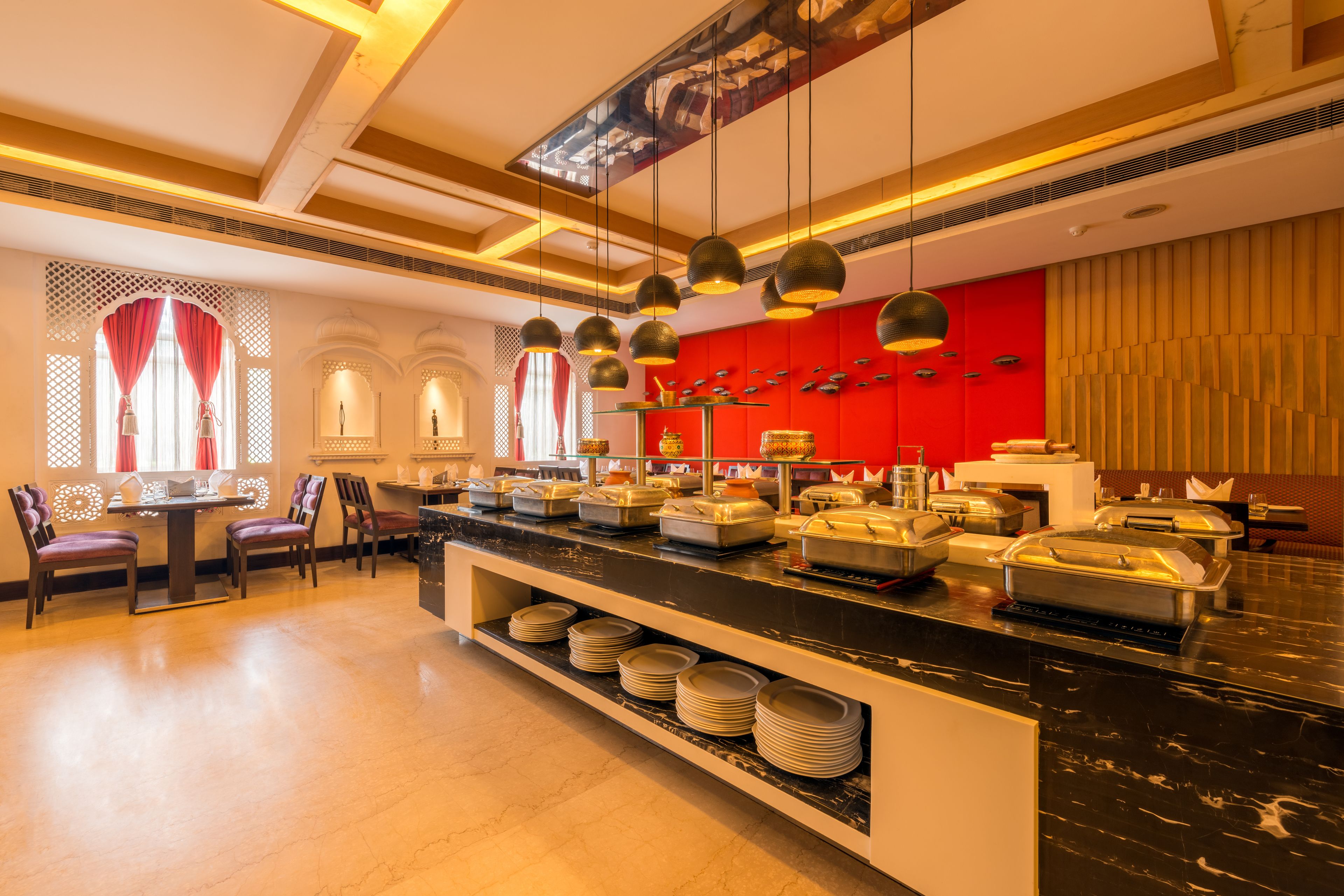 A buffet setup with a marble counter, multiple serving stations, and a red accent wall.
