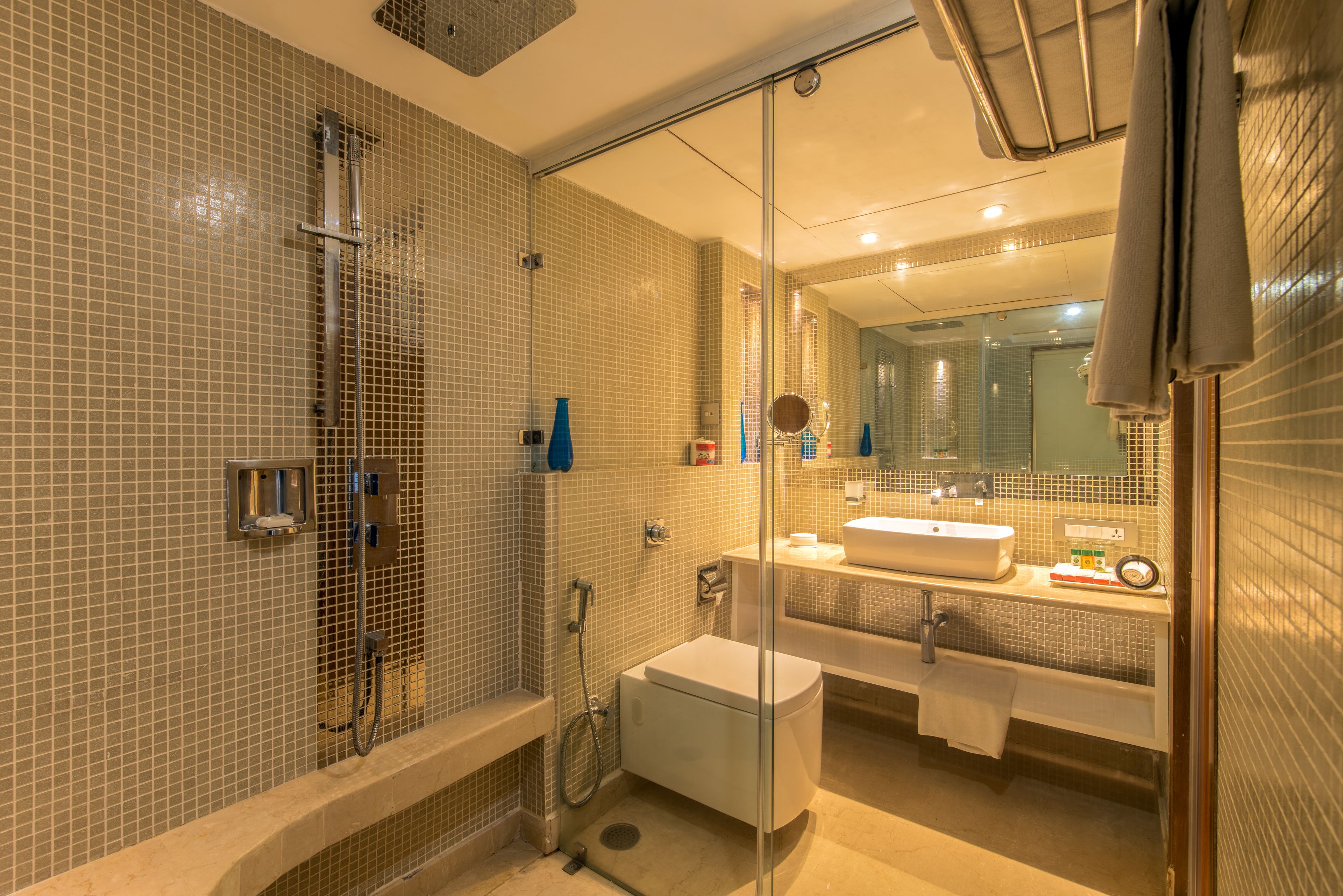 A modern bathroom with a glass-enclosed shower, a white sink, and a large mirror.