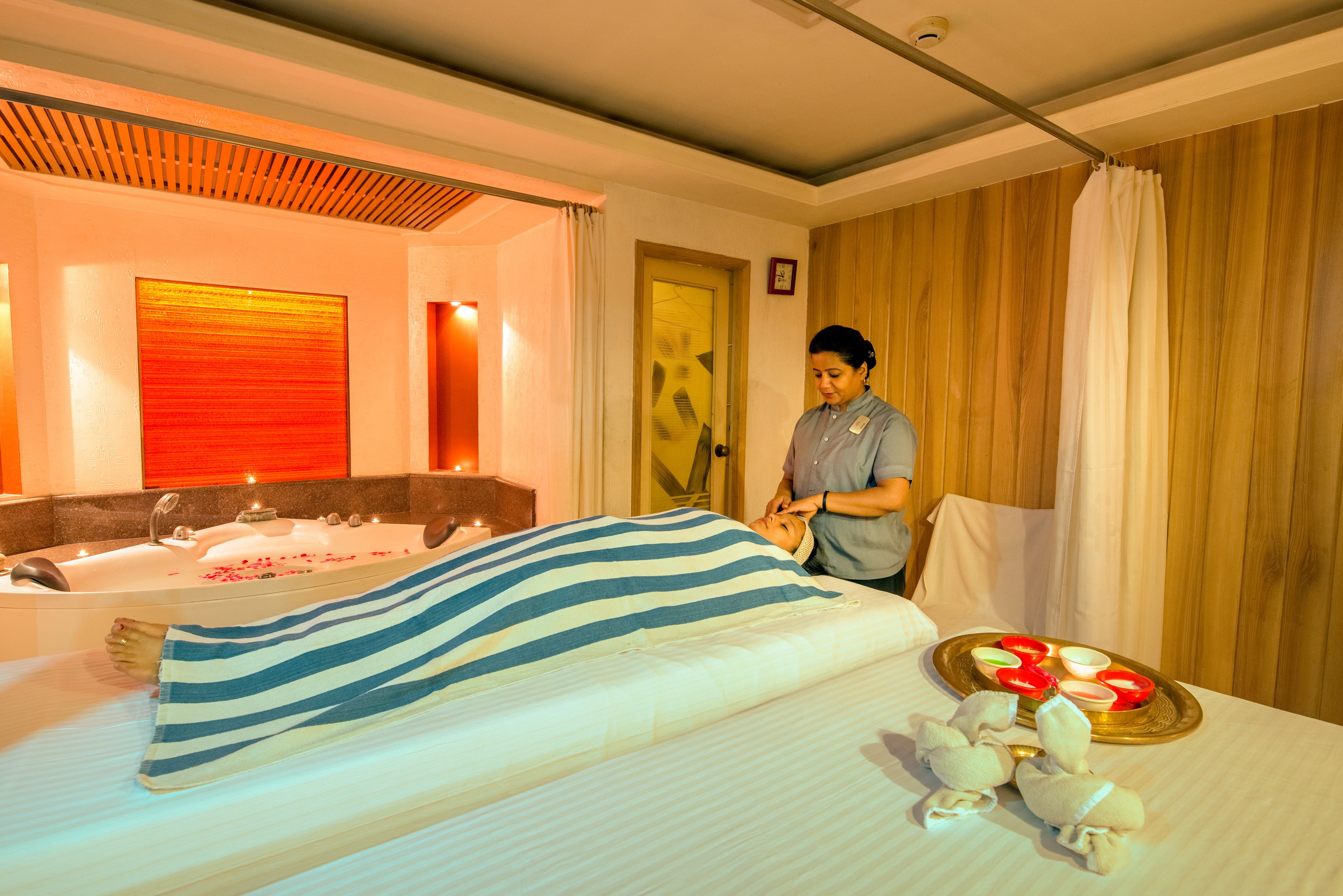 Una habitación de hotel con una cama grande, una bañera y una bandeja de fruta sobre la cama.